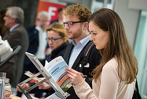 Eine Frau an einem Messestand mit der Fördermittel-Broschüre von co2online